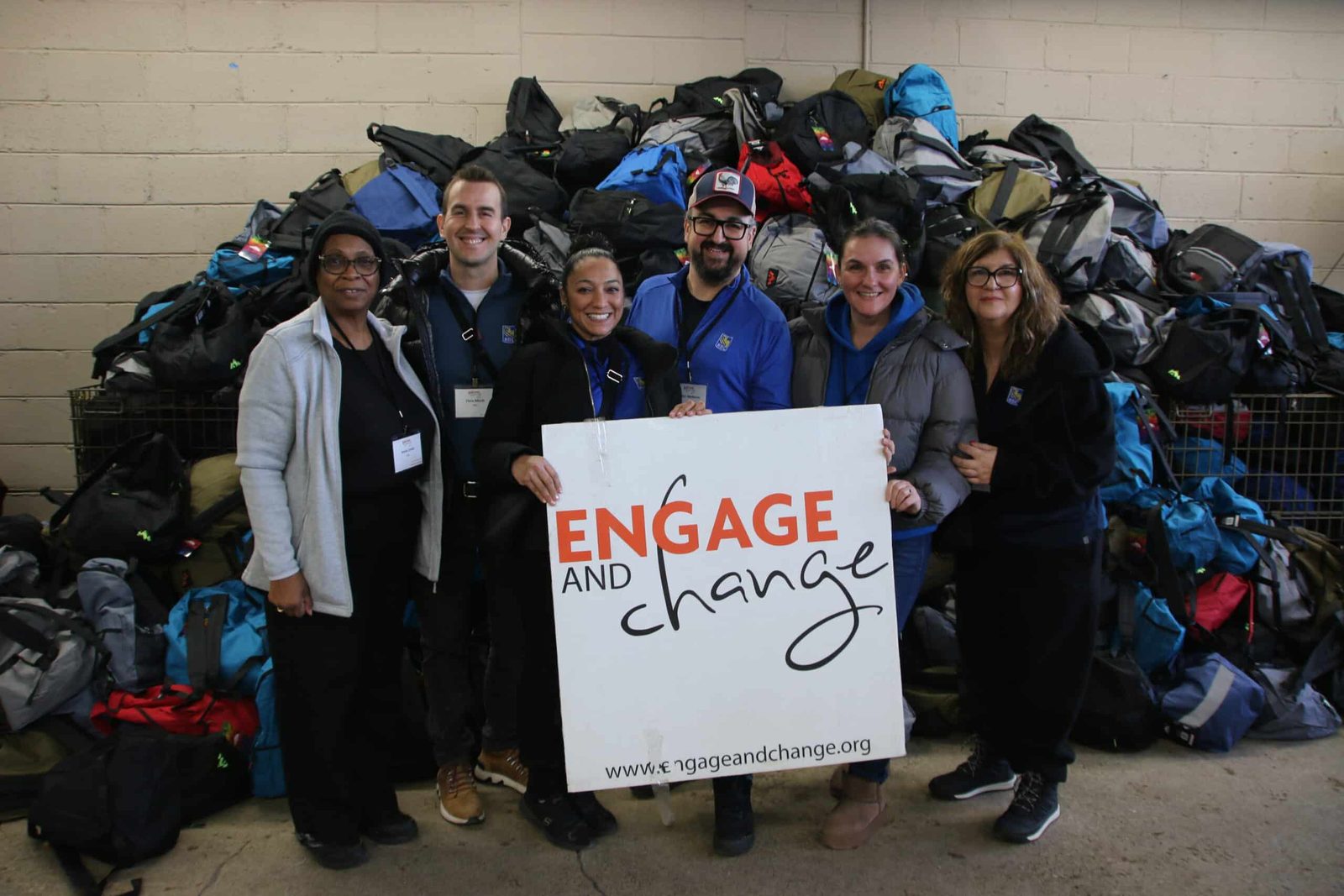Volunteers with the Engage and Change sign in front of thousands of packed kits